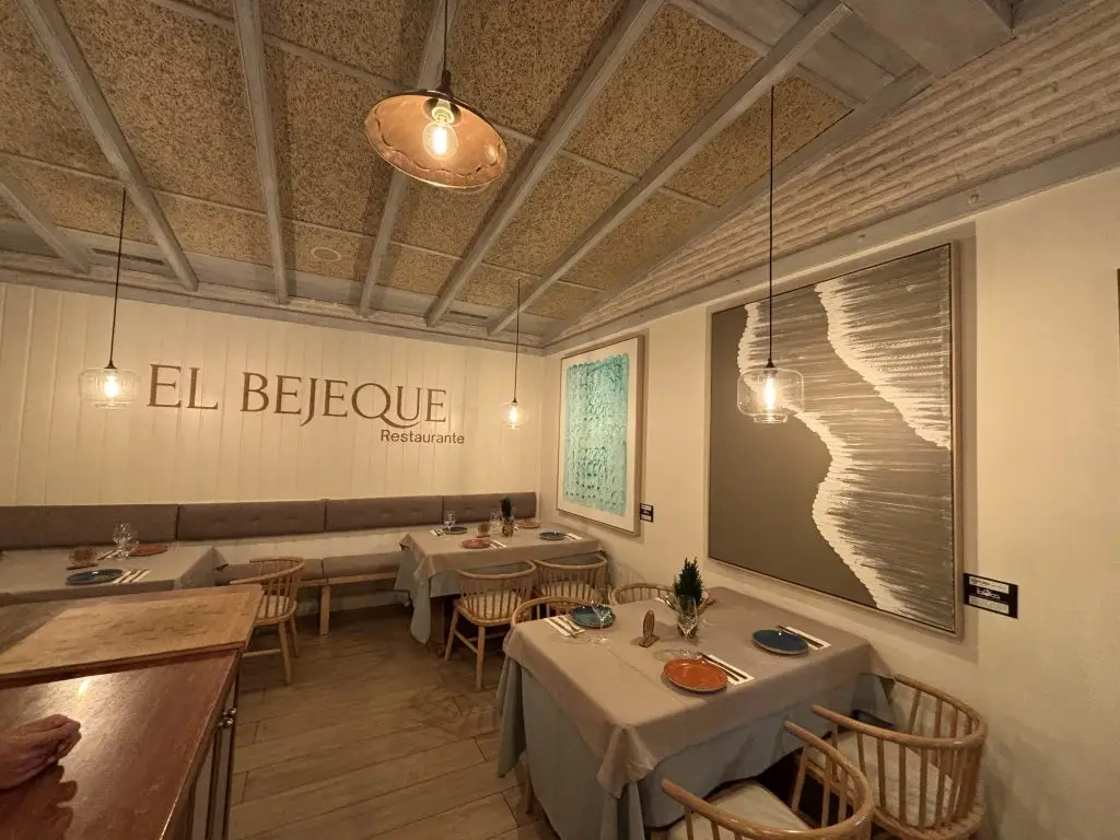 Interior del restaurante El Bejeque con mesas y lámparas de techo