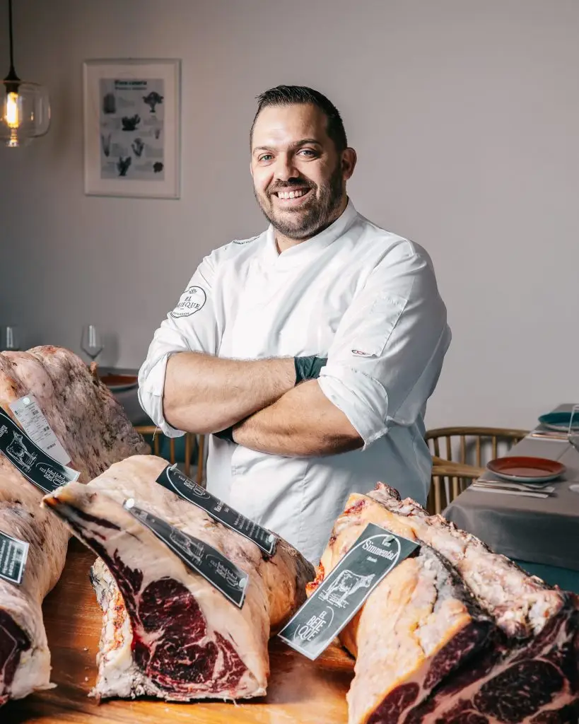 Chef Ayoze con brazos cruzados junto a cortes de carne madurada