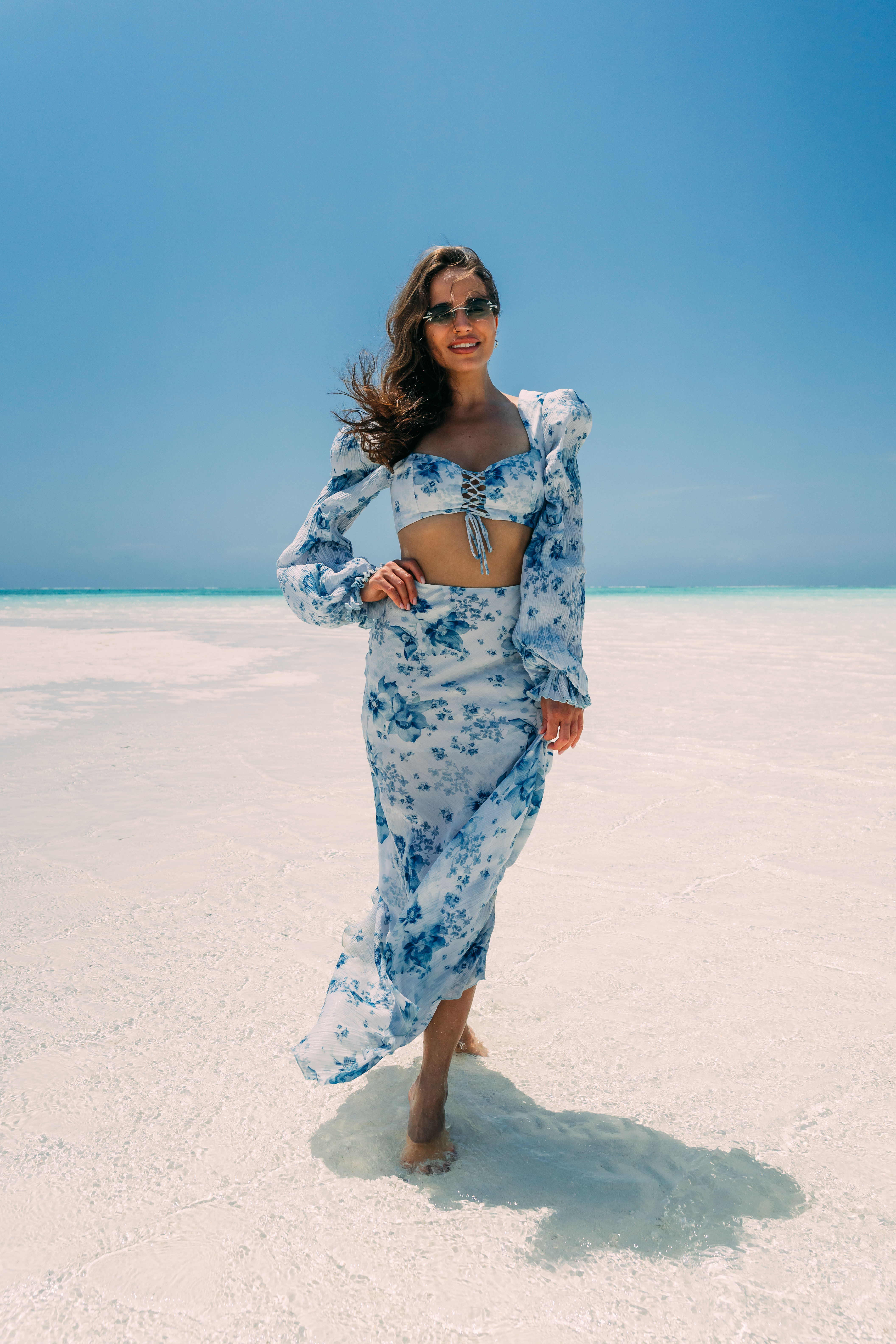 Woman in blue floral outfit standing in shallow water at Nungwi secret beach Zanzibar