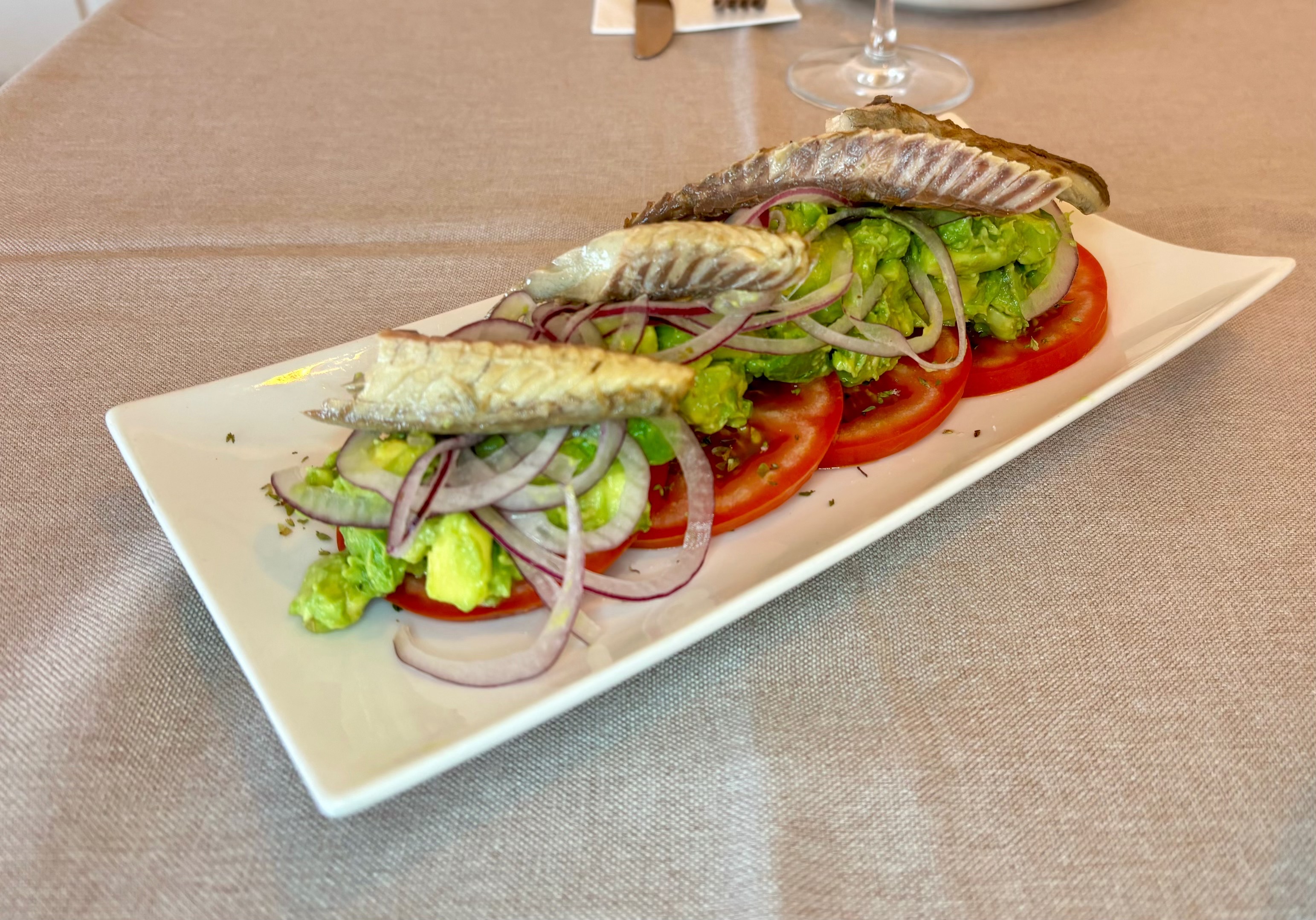 Pescado frito sobre ensalada con tomate y cebolla roja